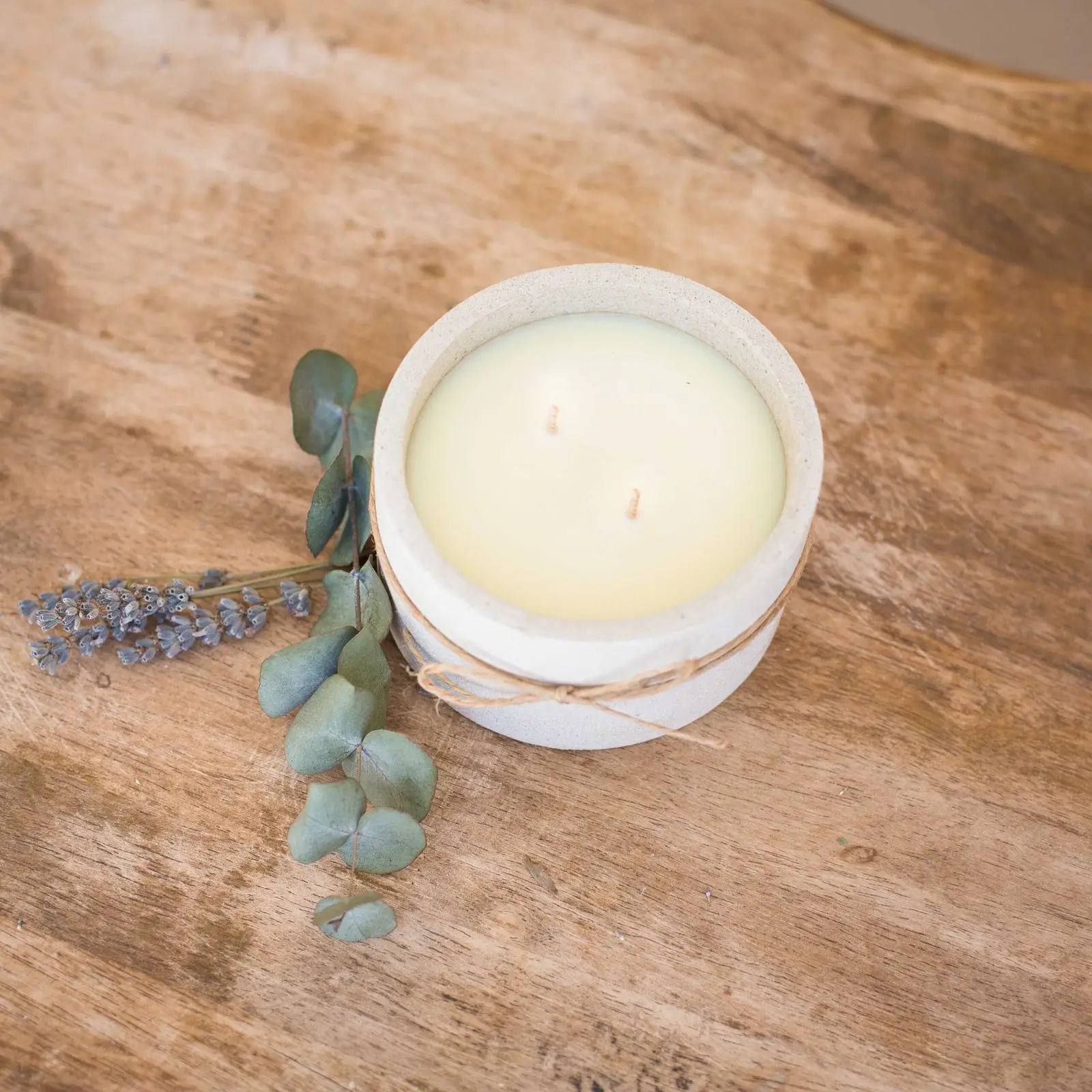 Unwrapped beeswax candle in vessel made from repurposed construction rubble and sand