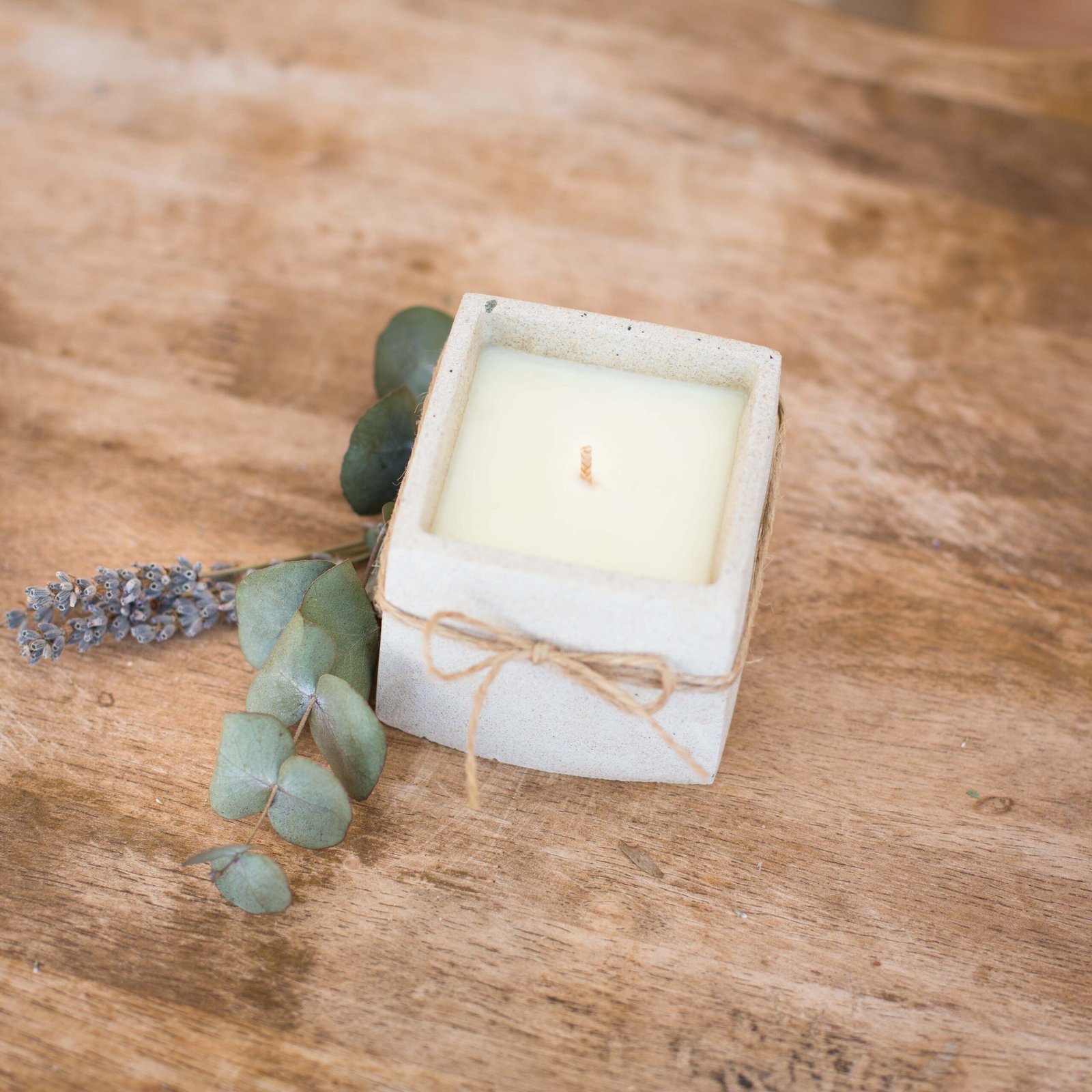 Unwrapped beeswax candle in vessel made from repurposed construction rubble and sand