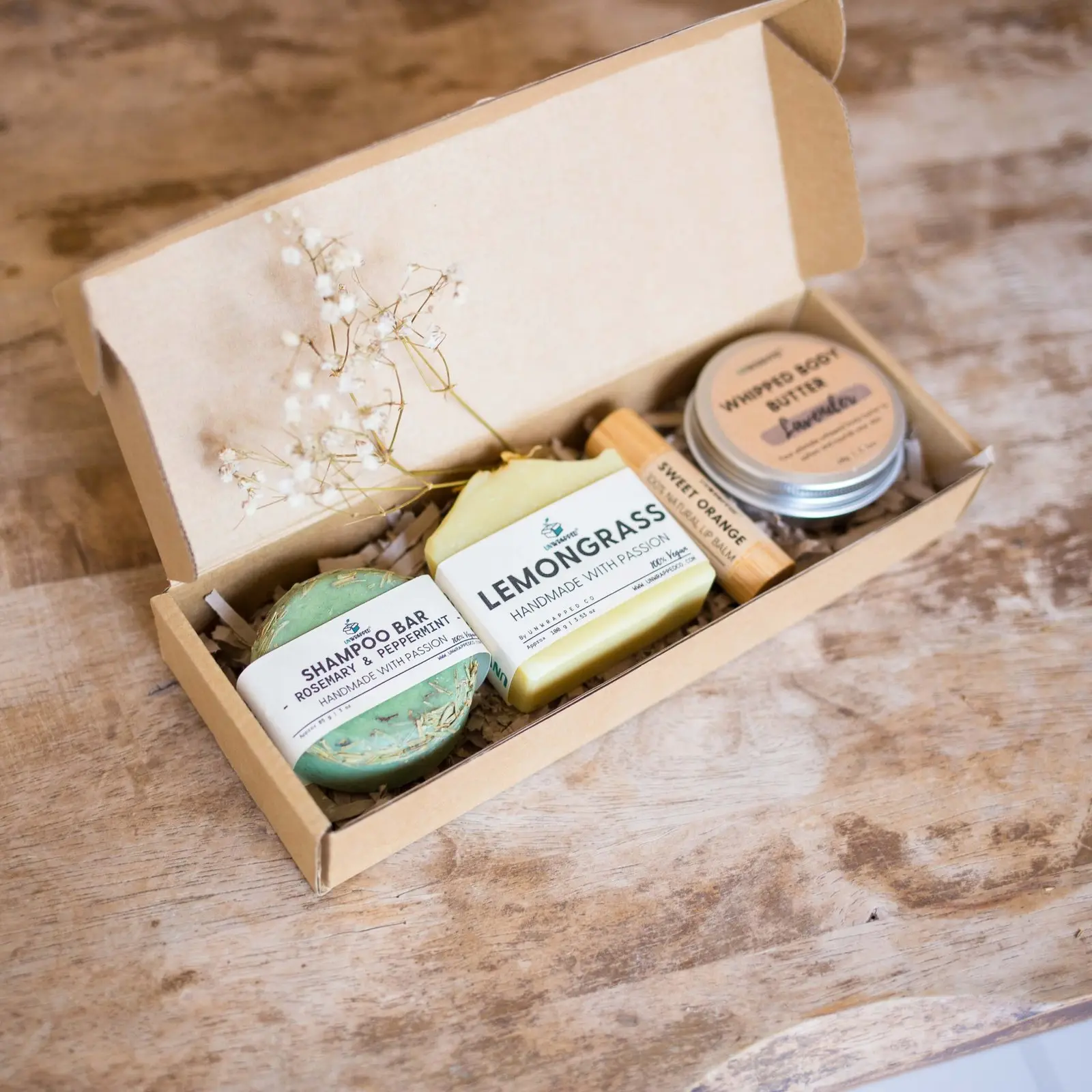 Unwrapped travel set with soap bar, shampoo bar, lip balm and whipper body butter in a natural box