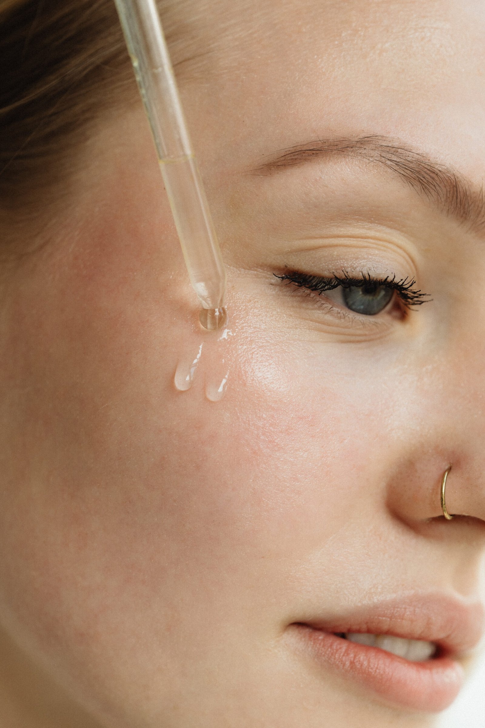 Woman applying Unwrapped facial serum to cheek